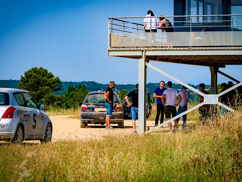 Participants au pied de la tour de contrôle, voiture de rallye garée à côté